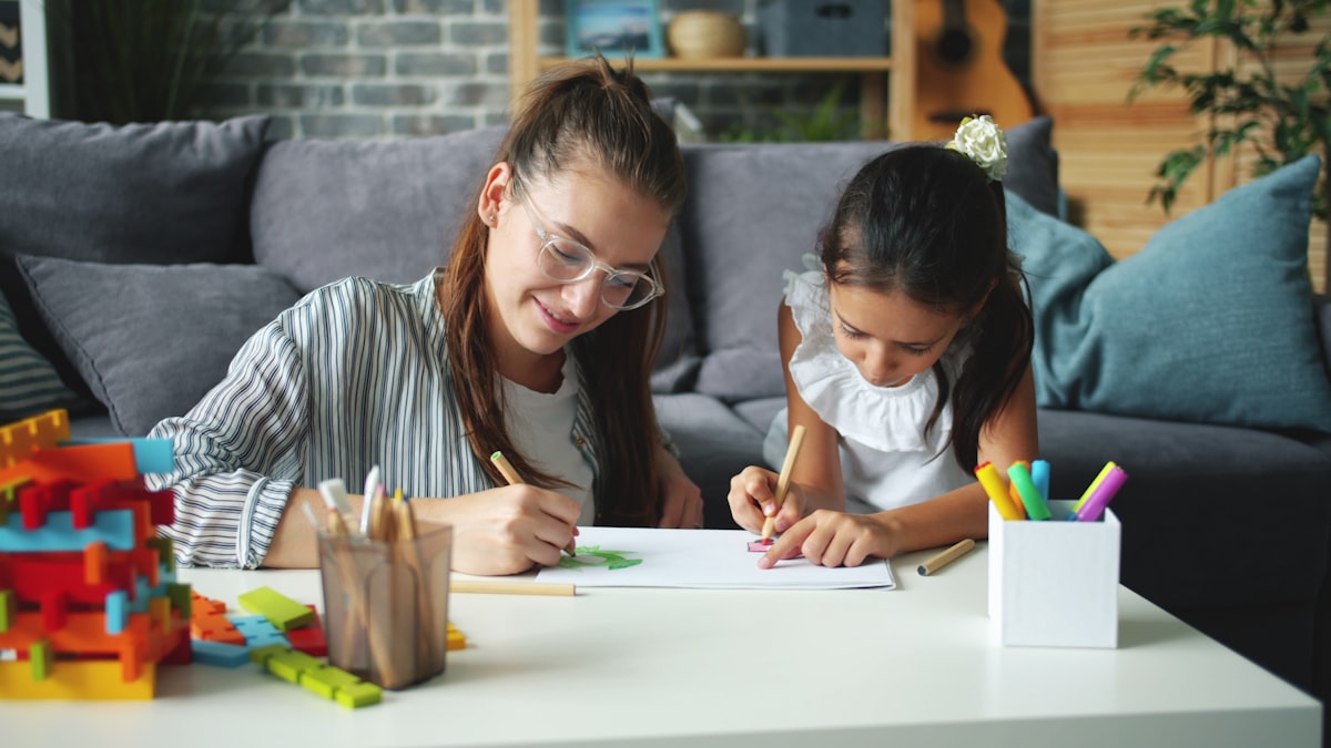 Une accompagnante et une enfant dessinent ensemble