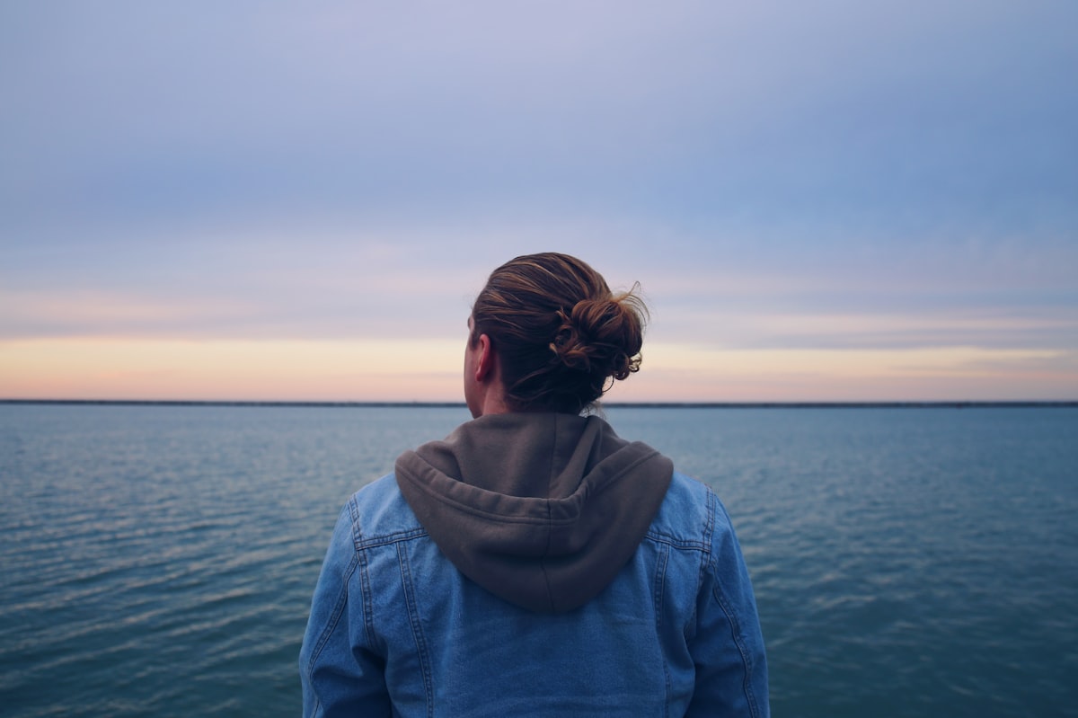 Une adolescente regarde l’horizon face à la mer